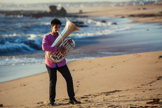 Musician play to Tuba on ocean shore.