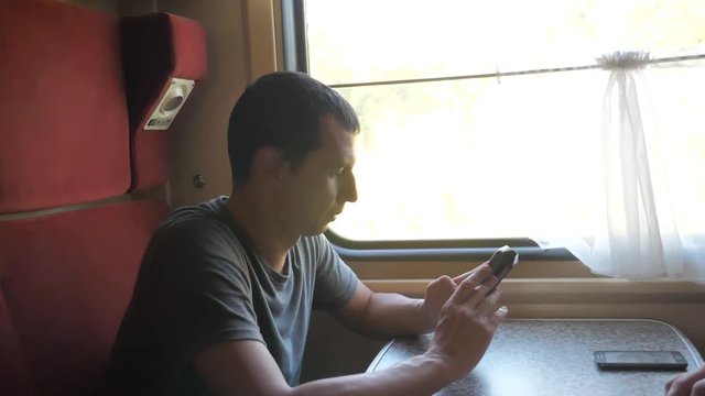 man traveler Relaxing On Train Listening To Music and smiling through the pictures via social media. slow motion video . uploading photo using cell phone while lifestyle riding home by train wagon