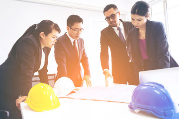 Group of Asian business people or engineers and architects with partner meeting or discussing start up new project or Security structure with blueprint and engineering objects on workplace at office
