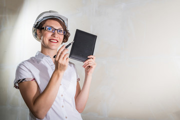Cute young woman in white construction protection building helmet in unfinished apartment © keleny