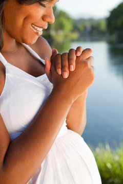 Young African American pregnant woman praying for her baby