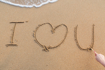 Fototapeta na wymiar Message i love you on the sand with woman hand drawing