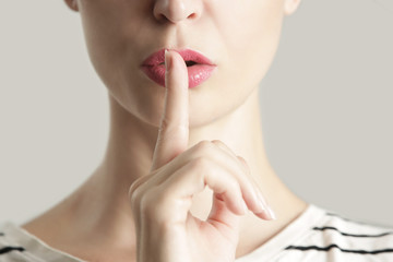 Finger on lips - silent gesture, Woman holding her finger to her lips in a gesture for silence.