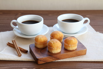 木のテーブルにのせた カップケーキ ホット コーヒー カップ