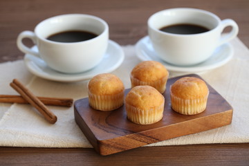 木のテーブルにのせた カップケーキ ホット コーヒー カップ