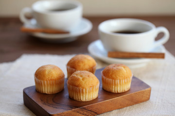 木のテーブルにのせた カップケーキ ホット コーヒー カップ