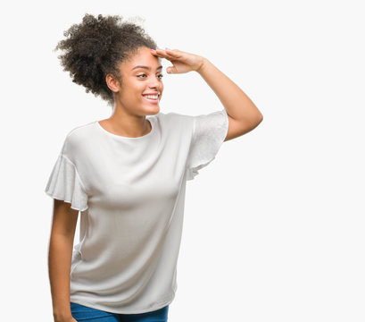 Young afro american woman over isolated background very happy and smiling looking far away with hand over head. Searching concept.