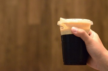 The hand holding a cup of cold nitro black coffee using a sip cup that no need to use straw for...
