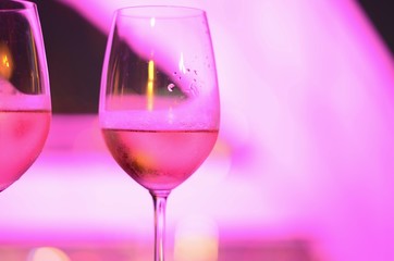 Two glasses of Rosé wine with bokeh light at Bangkok city and colorful light from rooftop building.