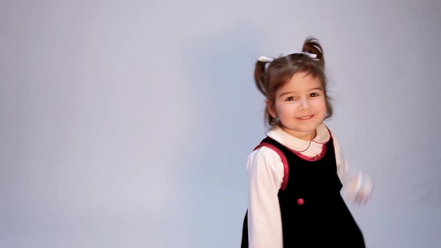 Adorable, high energy girl with pig tails turns to wind up to be silly.  She turns back with both arms outstretched and rocks from side to side with her tongue sticking out, making funny faces.