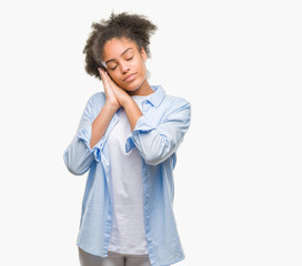 Young afro american woman over isolated background sleeping tired dreaming and posing with hands together while smiling with closed eyes.