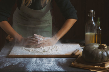 Women's hands knead the dough. Baking ingredients on wooden table