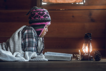 Boy reading holy bible in home with  light  of oil lamp.