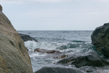 Waves are beating against rocks on the seashore, the ocean in cloudy weather.