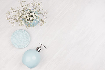 Pastel blue smooth ceramic round bowls with white flowers for soft bathroom decoration on white wood background with copy space, top view.