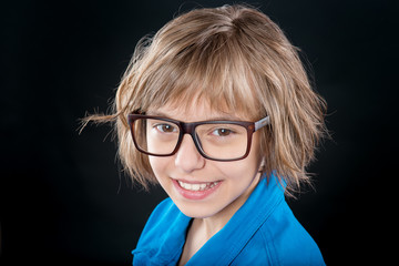 Emotional portrait of attractive caucasian little student girl with eyeglasses. Funny cute smiling child looking at camera on black background.