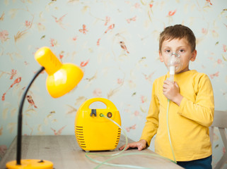 Fototapeta premium cute little caucasian boy making inhalation at home using electric medical gear