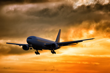 Scenic view on silhouette of modern passenger jet engine airplane landing to airport runway at dusk...
