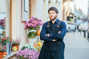 Portrait of thoughtful handsome business man florist standing before his floral store with city...