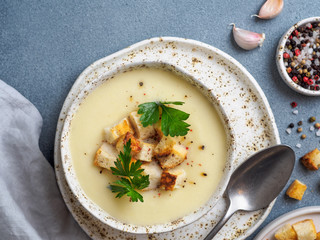 cauliflower potato soup puree on stone background, Creamy cauliflower soup with toasted bread croutons. Vegetarian healthy food concept. Ideas and recipes for winter meal. Top view flat lay.Copy space