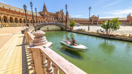 Daily boat trip at Plaza de Espana. River with boats and moving people in Seville, Andalusia, Spain