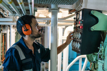 Marine engineer officer in engine control room ECR. Seamen's work. He starts or stops main engine...