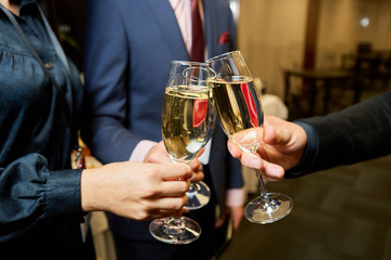 Cheers! Group of people cheering with champagne flutes with restaurant interior in the background