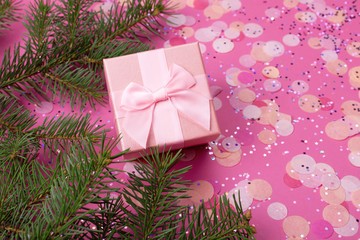 Christmas gifts with pink ribbon on pink pastel background with festive decorations. Christmas background with copy space.