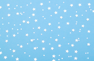 Christmas pattern made of silver stars on blue background. Winter concept. Flat lay.