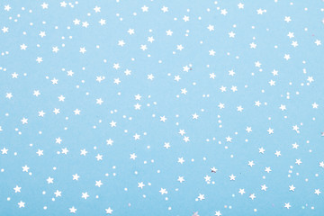 Christmas pattern made of silver stars on blue background. Winter concept. Flat lay.