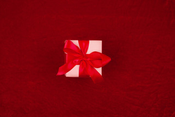 Christmas gift with red ribbon on red background with decorations. Christmas background with copy space.