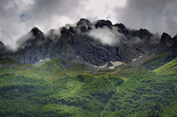 Peak of the mountain with glaciers against the background of clouds and sky. Caucasian ridge, Russia.