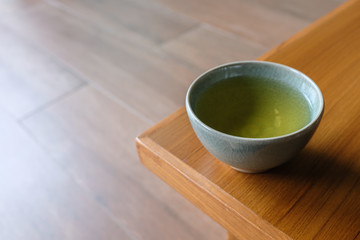 Close up of tea in blue ceramic cup on wooden table in a japanese tea room on blurred background