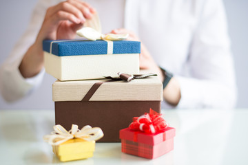 Closeup of person unpacking gift boxes. Person sitting at table. Gift concept. Cropped view.