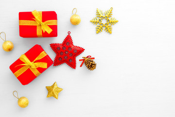 Christmas composition.  Red gift boxes, star, gold ball, pine cone and snowflake on white background. Creative flat lay, border and copy space