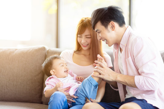 Happy Family Mother And Father Playing With Baby At Home