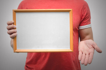 Man is holding a blank diploma or certificate frame border with copy space isolated on gray background.