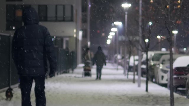 People on winter city street at snowfall. Slow motion