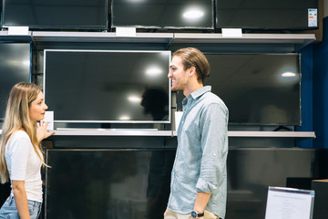 Young woman and man buying a television in a store