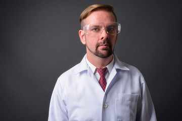 Blond bearded man doctor with goatee against gray background