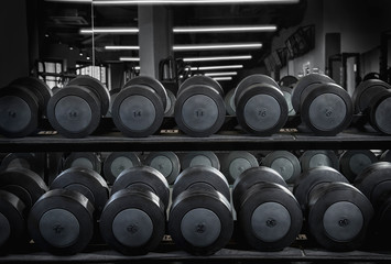 Black metal dumbbell set. Close up many metal dumbbells on rack in gym