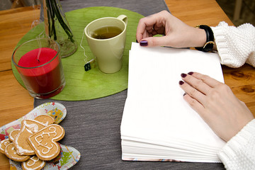 hot green tea in women's hands, a book and ginger cookies for Christmas