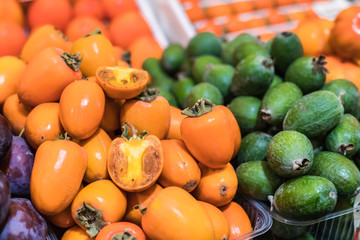 uicy southern seasonal fruit a sweet persimmon and a feijoa are laid out by the hill on a counter of shop