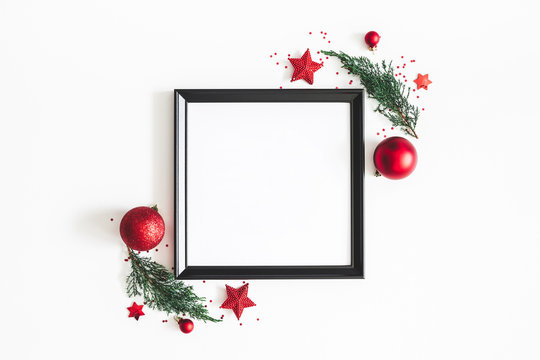 Christmas composition. Photo frame, red decorations, fir tree branches on white background. Christmas, winter, new year concept. Flat lay, top view, copy space