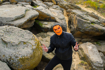 Man in a pumpkin mask in the mountains.