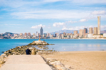 Couple eldery people sitting against sea and watching at Benidorm city