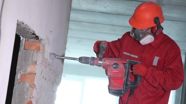 worker with demolition hammer breaking interior wall