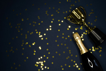 gold winning cup and champagne bottle  on dark blue background , success concept
