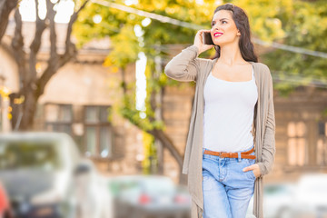 Cute young woman using cellphone in urban surroundings.