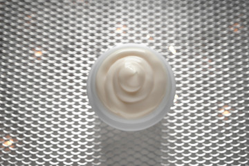 Jar with body cream on shiny grid
